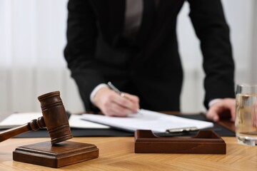 Lawyer working with documents at wooden table, focus on gavel