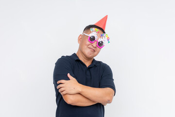 A middle-aged Asian man looking composed while celebrating his birthday in a party hat and novelty...