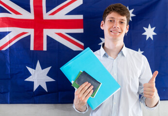 Young guy posing with documents against background of Australian flag