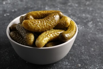 Tasty pickled cucumbers in bowl on grey table, closeup