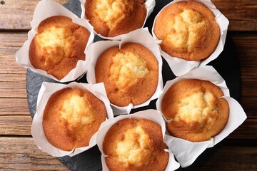 Delicious sweet muffins on wooden table, top view