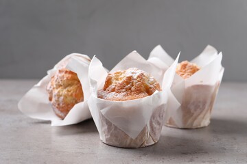 Delicious muffins with powdered sugar on grey table, closeup