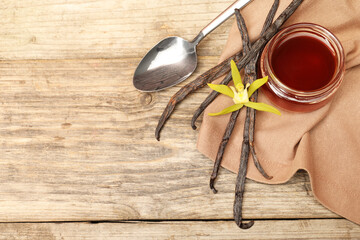 Aromatic vanilla extract, pods and flower on wooden table, flat lay. Space for text