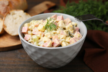 Tasty Olivier salad with boiled sausage in bowl on table, closeup
