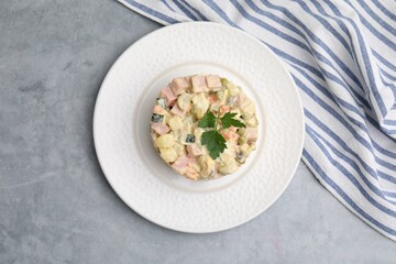 Tasty Olivier salad with boiled sausage on grey table, top view
