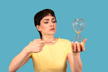 portrait of a serious irritated angry woman holding an hourglass sand timer, aging, deadline...