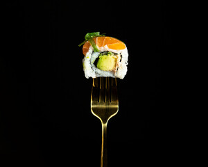 Japanese salmon sushi on a fork on the dark background