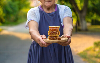 An elderly woman holds honey in her hands, selective focus.