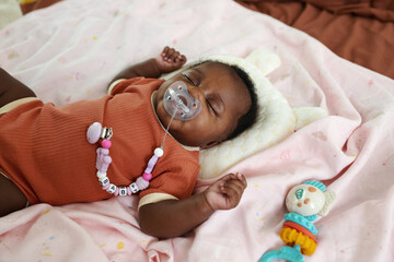 Newborn baby girl sleeping with pacifier in mouth