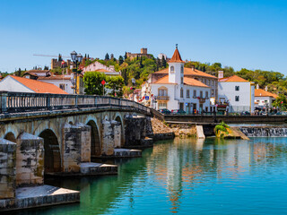 Fototapeta na wymiar Old bridge (Ponte Vhela) over Nabao river, leading to the historic centre of Tomar, picturesque village in Santarem District, Portugal