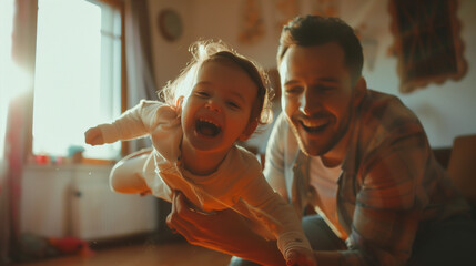 Father playing airplane with his toddler daughter, both smiling joyfully