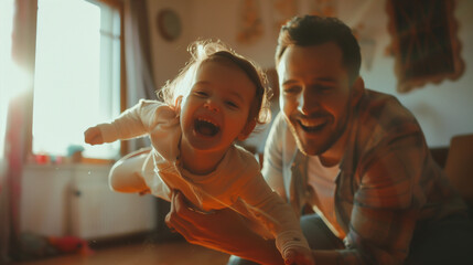 Obraz premium Father playing airplane with his toddler daughter, both smiling joyfully