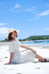 a beautiful girl wearing a beach dress is enjoying her summer vacation on Mandalika beach with sunny weather and blue skies