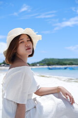 a beautiful girl wearing a beach dress is enjoying her summer vacation on Mandalika beach with sunny weather and blue skies