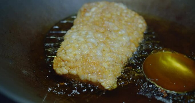 Cooking Crispy golden-brown pork skin in hot oil, sizzling in a deep frying pan, capturing the essence of delicious thai cuisine
