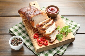 Pieces of baked pork belly served with sauce, chili pepper and parsley on wooden table