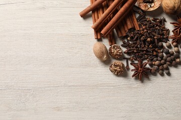 Different spices and nuts on wooden table, flat lay. Space for text