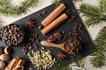 Fototapeta na wymiar Different spices and fir branches on wooden table, flat lay