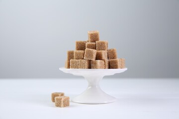 Brown sugar cubes on white table against light background