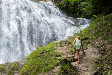 Tourist woman walks towards a waterfall, in the Peruvian jungle.