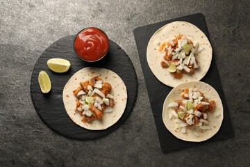 Delicious tacos with vegetables, meat and ketchup on grey textured table, flat lay