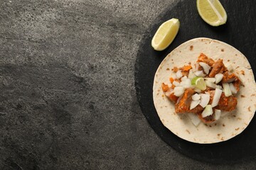 Delicious taco with vegetables, meat and lime on grey textured table, top view. Space for text