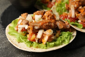 Delicious tacos with vegetables and meat on grey textured table, closeup