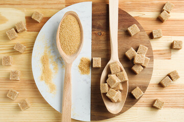 Brown sugar cubes and granulated in spoons on wooden table, flat lay