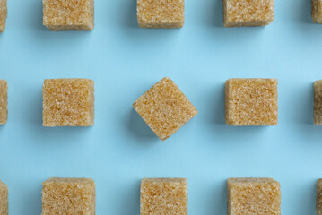 Brown sugar cubes on light blue background, flat lay