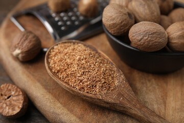 Spoon with grated nutmeg, seeds and grater on table, closeup