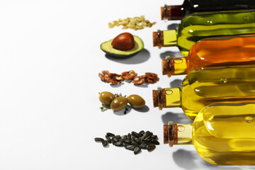 Vegetable fats. Different cooking oils in glass bottles and ingredients on white background, space...