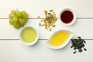 Vegetable fats. Different cooking oils in bowls and ingredients on white wooden table, flat lay