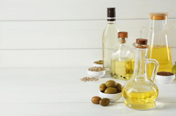 Vegetable fats. Different cooking oils in bottles and ingredients on white wooden table, space for text
