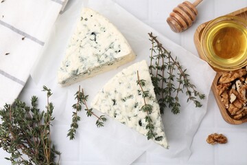 Tasty blue cheese with thyme, walnuts and honey on white tiled table, flat lay
