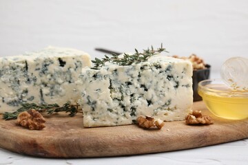 Tasty blue cheese with thyme, honey and walnuts on white table, closeup