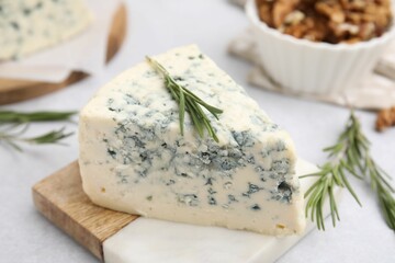 Tasty blue cheese with rosemary on light table, closeup