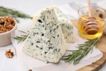 Tasty blue cheese with rosemary, honey and walnuts on white table, closeup