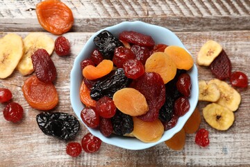 Mix of delicious dried fruits on wooden table, flat lay