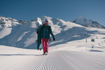Female snowboarder walking on Snow trail from ratrak preparation, freshly groomed ski slope in high...