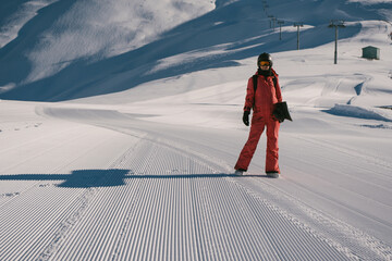 Female snowboarder walking on Snow trail from ratrak preparation, freshly groomed ski slope in high mountains ski resort