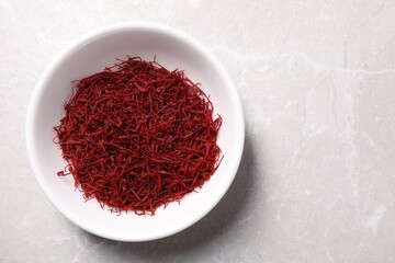 Aromatic saffron in bowl on light gray table, top view. Space for text