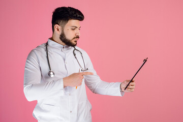 Side view of brunette doctor, intern holding folder, looking, pointing by finger, posing indoors....