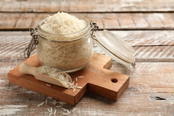 Raw basmati rice in glass jar and scoop on wooden table