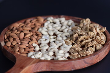 Exquisite arrangement of almonds, cashews, and walnuts on a rustic wooden tray, perfect for healthy snacks and gourmet presentations.