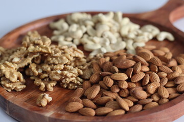 Exquisite arrangement of almonds, cashews, and walnuts on a rustic wooden tray, perfect for healthy snacks and gourmet presentations.