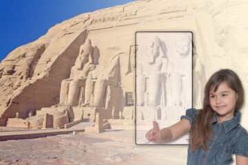 Little tanned girl is pointing a finger at a blank smartphone screen with famous temple in Abu Simbel in Egypt in the background. Travel concept with free space for your text.
