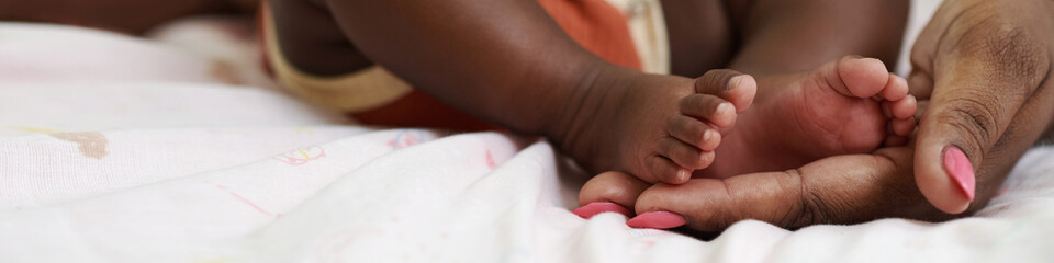 Obraz na płótnie Canvas Header with mother touching feet of newborn baby