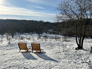 Two comfortable wooden benches, similar to sun loungers, are installed on a raised platform overlooking the winter valley.