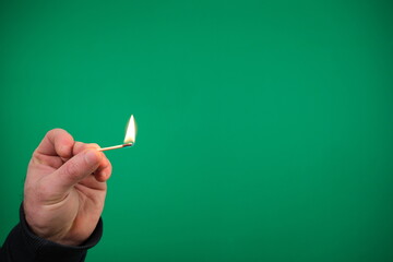 Lit matchstick held in hand by Caucasian male hand studio shot isolated advertising Green...