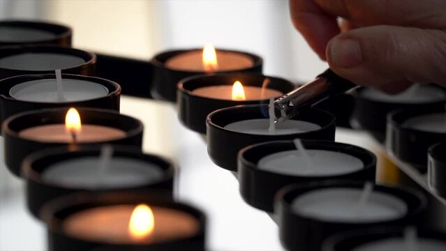 Slow motion, closeup, person lighting a candle for prayers in the church.
